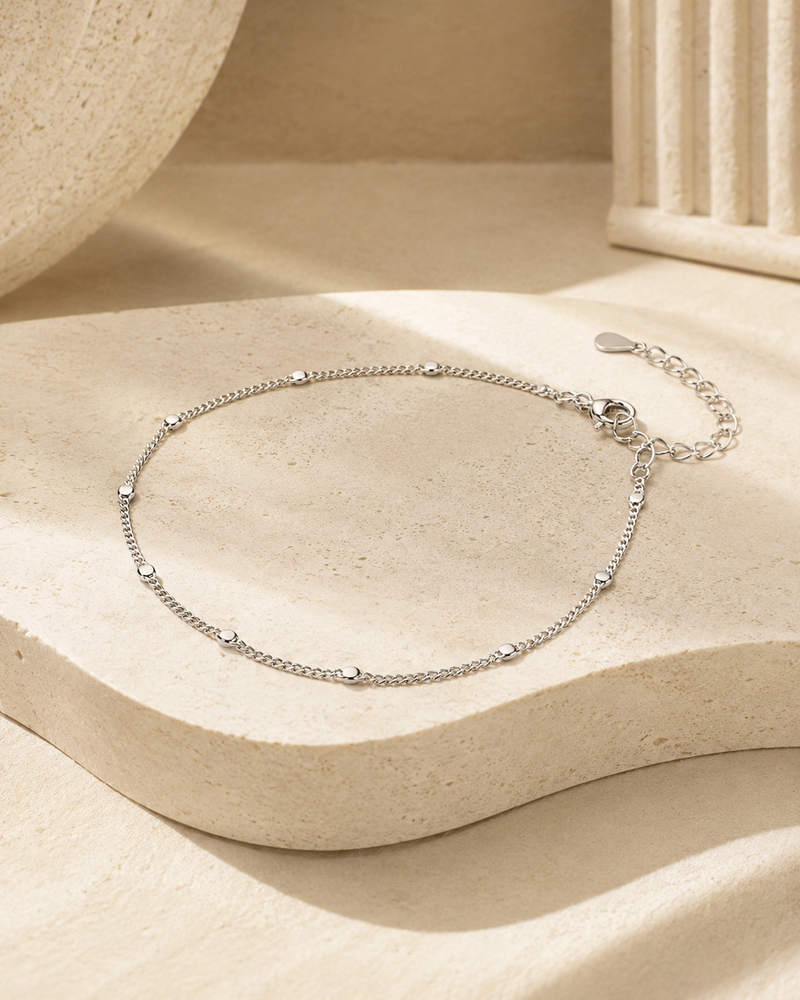 Pulsera UNIQUE de NYXIDIE: cadena de plata de ley 925 con esferas pulidas, sobre piedra travertino.